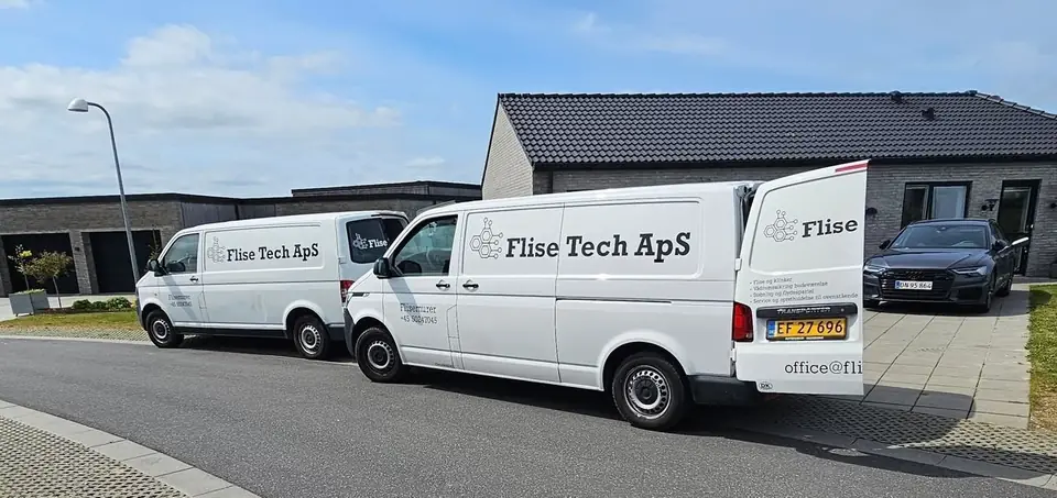 To hvide Flise Tech ApS-varebiler holder foran et nybygget parcelhus i Østjylland