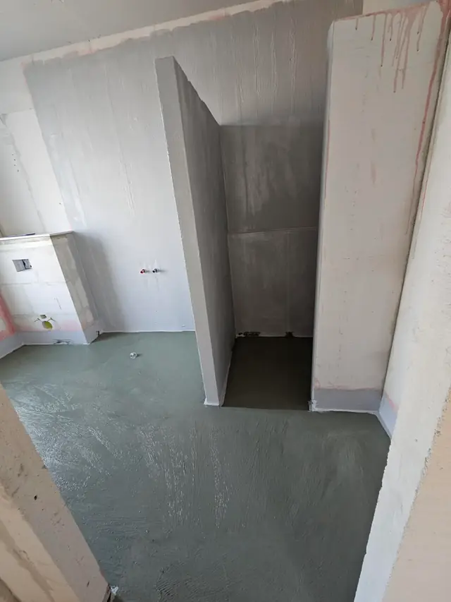 Badeværelse med primer på vægge og gulv, hvor bruseniche og installationsvæg står færdigt opbygget
